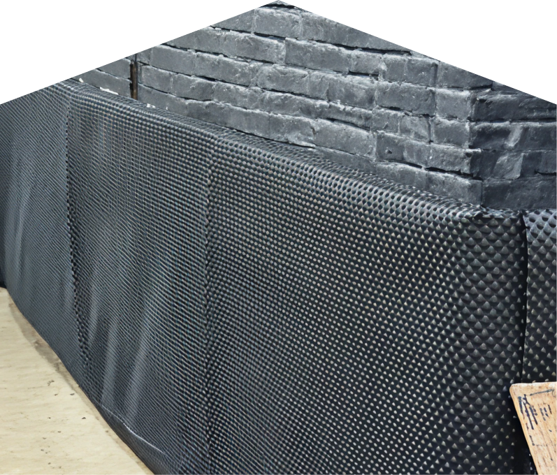 Exterior basement waterproofing completed by M&K , showing a sealed foundation wall with dimpled waterproof membrane partially installed on a brick surface, preventing moisture infiltration. Exterior basement waterproofing completed by M&K, showing a sealed foundation wall with dimpled waterproof membrane partially installed on a brick surface, preventing moisture infiltration.