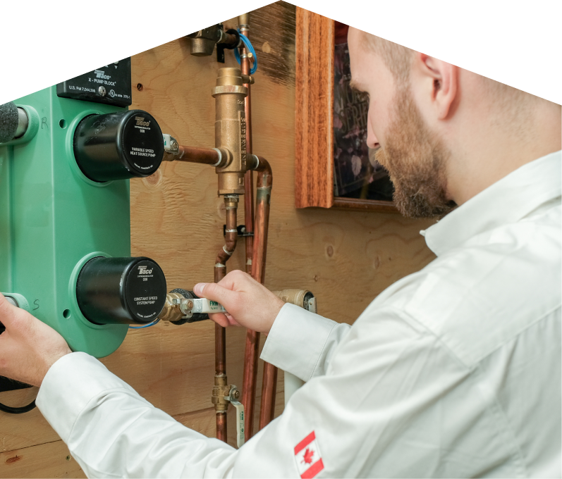 M&K HVAC specialist performing boiler installation, securing a valve on a new hydronic heating system with copper piping and a green circulation pump mounted on a wooden wall. M&K HVAC specialist performing boiler installation, securing a valve on a new hydronic heating system with copper piping and a green circulation pump mounted on a wooden wall.