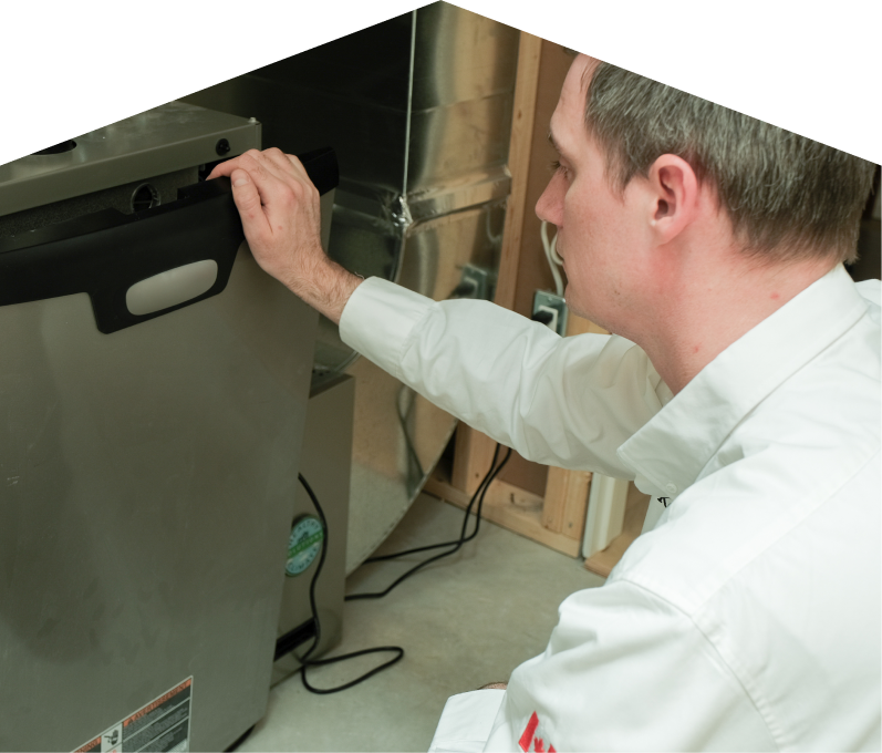 M&K HVAC professional installing a new furnace unit, aligning the front panel with surrounding ductwork and wiring in a residential utility space. M&K HVAC professional installing a new furnace unit, aligning the front panel with surrounding ductwork and wiring in a residential utility space.