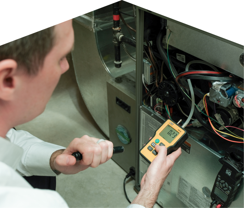 M&K HVAC specialist performing furnace repair on a heating system, using a digital manometer to check pressure. M&K HVAC specialist performing furnace repair on a heating sy