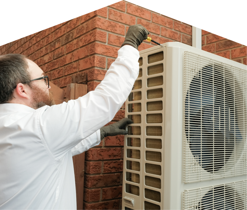 M&K HVAC specialist using a screwdriver to complete a heat pump installation beside a brick wall. M&K HVAC specialist using a screwdriver to complete a heat pump installation beside a brick wall.