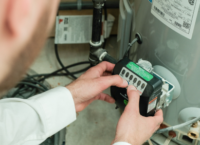 A M&K technician adjusts the control module on a residential water heater, verifying proper operating settings. A M&K technician adjusts the control module on a residential water heater, verifying proper operating settings.