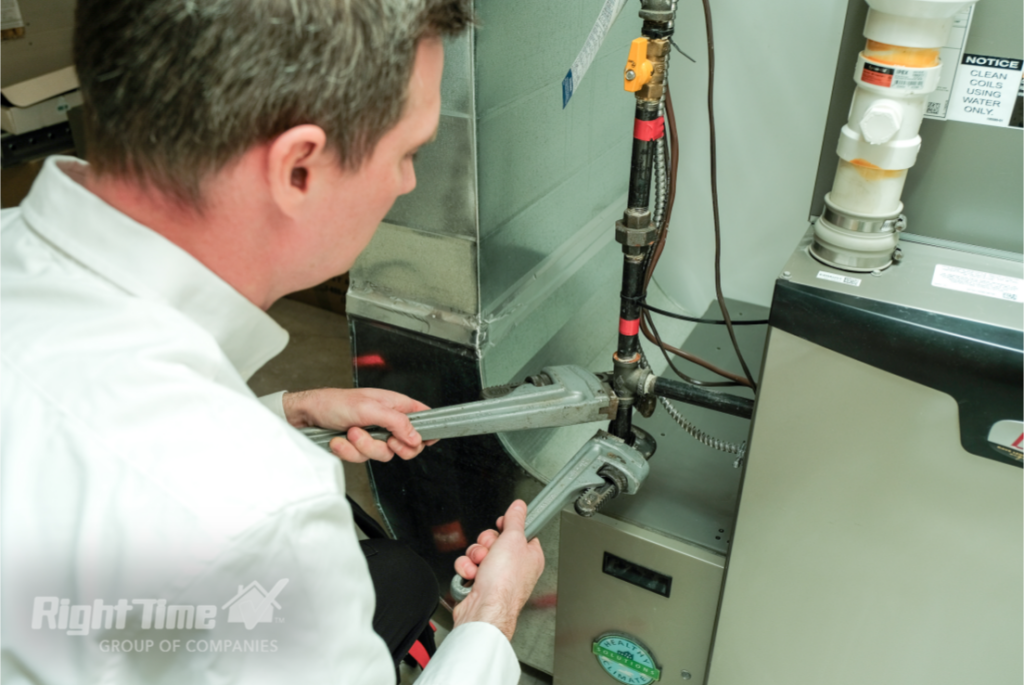 HVAC technician in London adjusting furnace connections with wrenches to address new furnace acetone smell issues during heating system maintenance